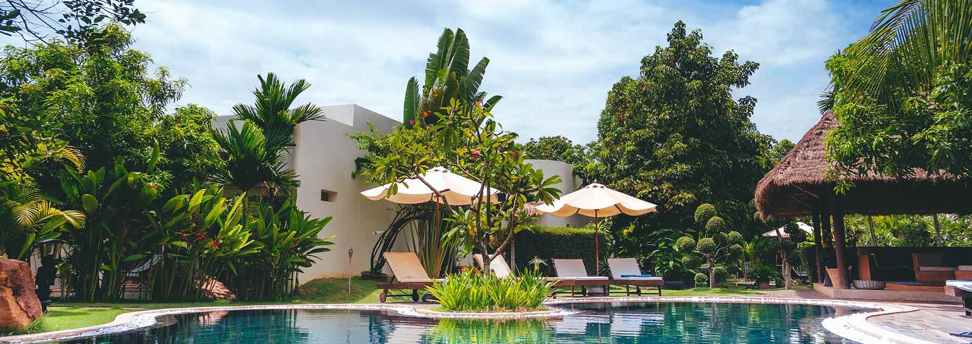 a pool surrounded by lush green trees and a lounge chair at The Discovery Park Life Apartments